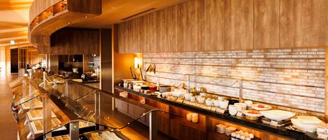 A buffet area with multiple food stations, a brick wall, and a wooden ceiling.