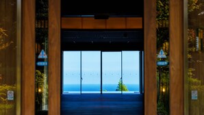 Una entrada de madera con vistas al mar a través de grandes puertas de vidrio.