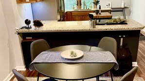 Una cocina compacta con una isla central, una mesa de comedor con sillas y vistas al exterior a través de una ventana.