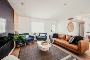Un salon moderne comprenant un canapé, des fauteuils, une table basse et un téléviseur.