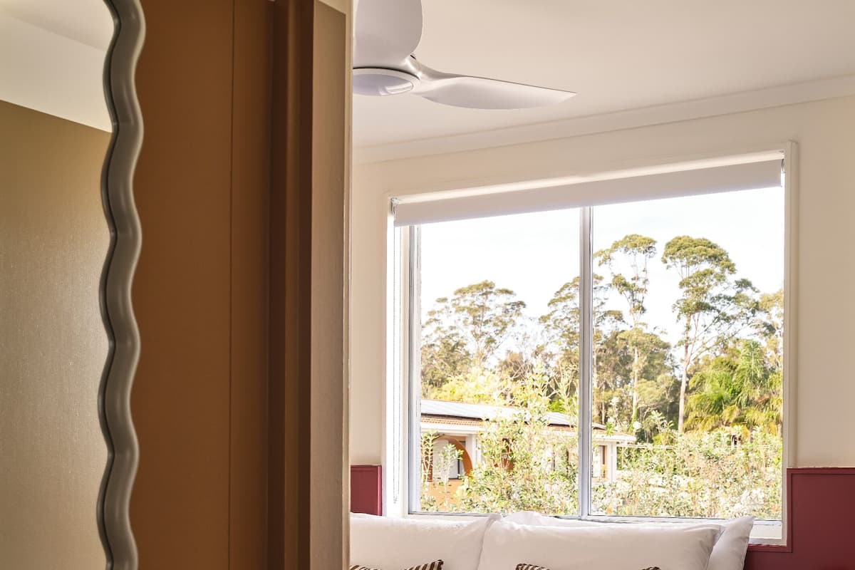 Un dormitorio con una cama, una ventana, un ventilador de techo y una lámpara.