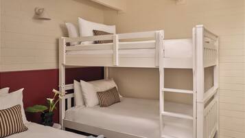 A bunk bed room with a white color scheme, a red accent wall, and a small plant.