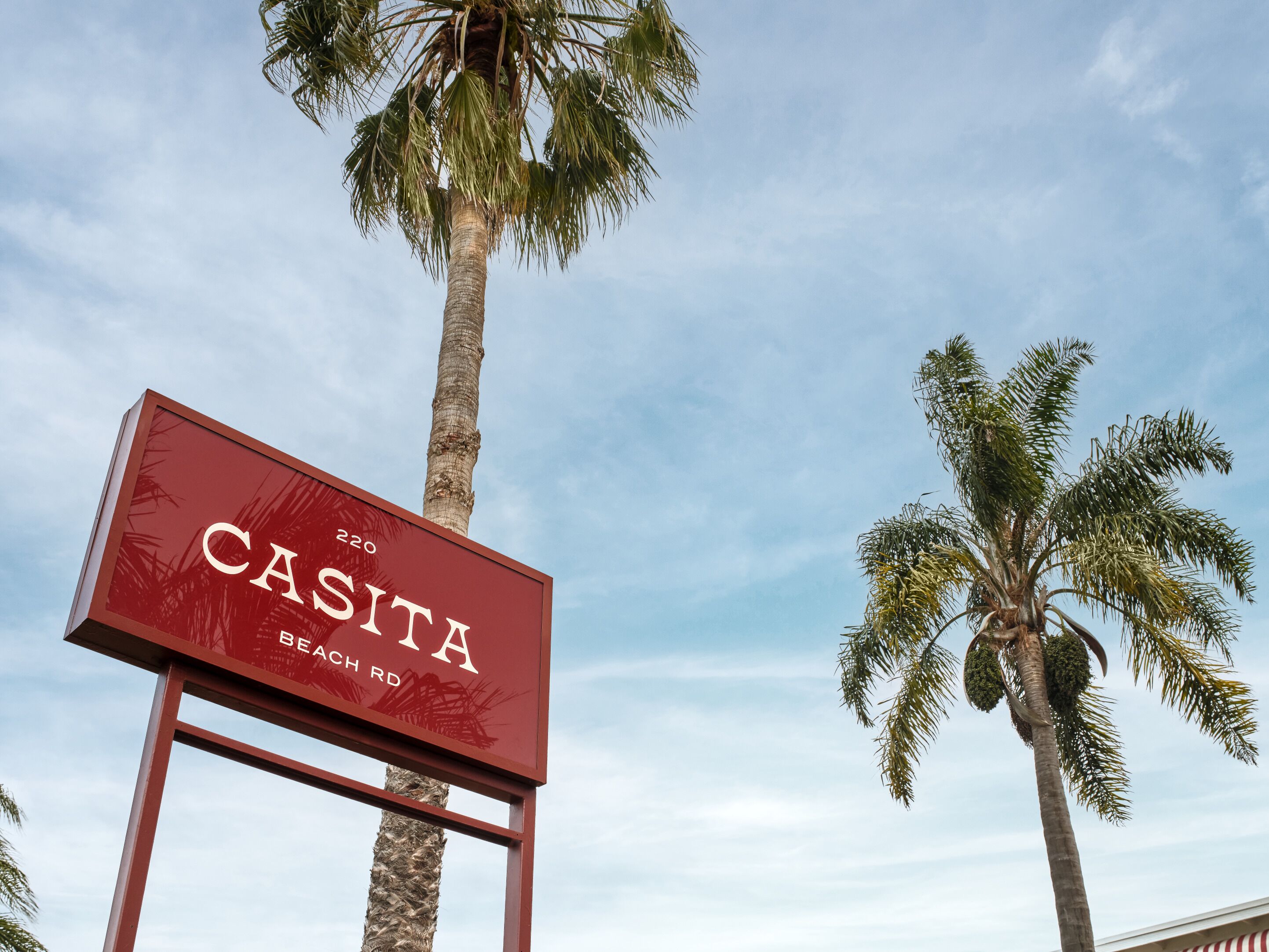 Un panneau indiquant « CASITA BEACH RD », avec des palmiers en arrière-plan.