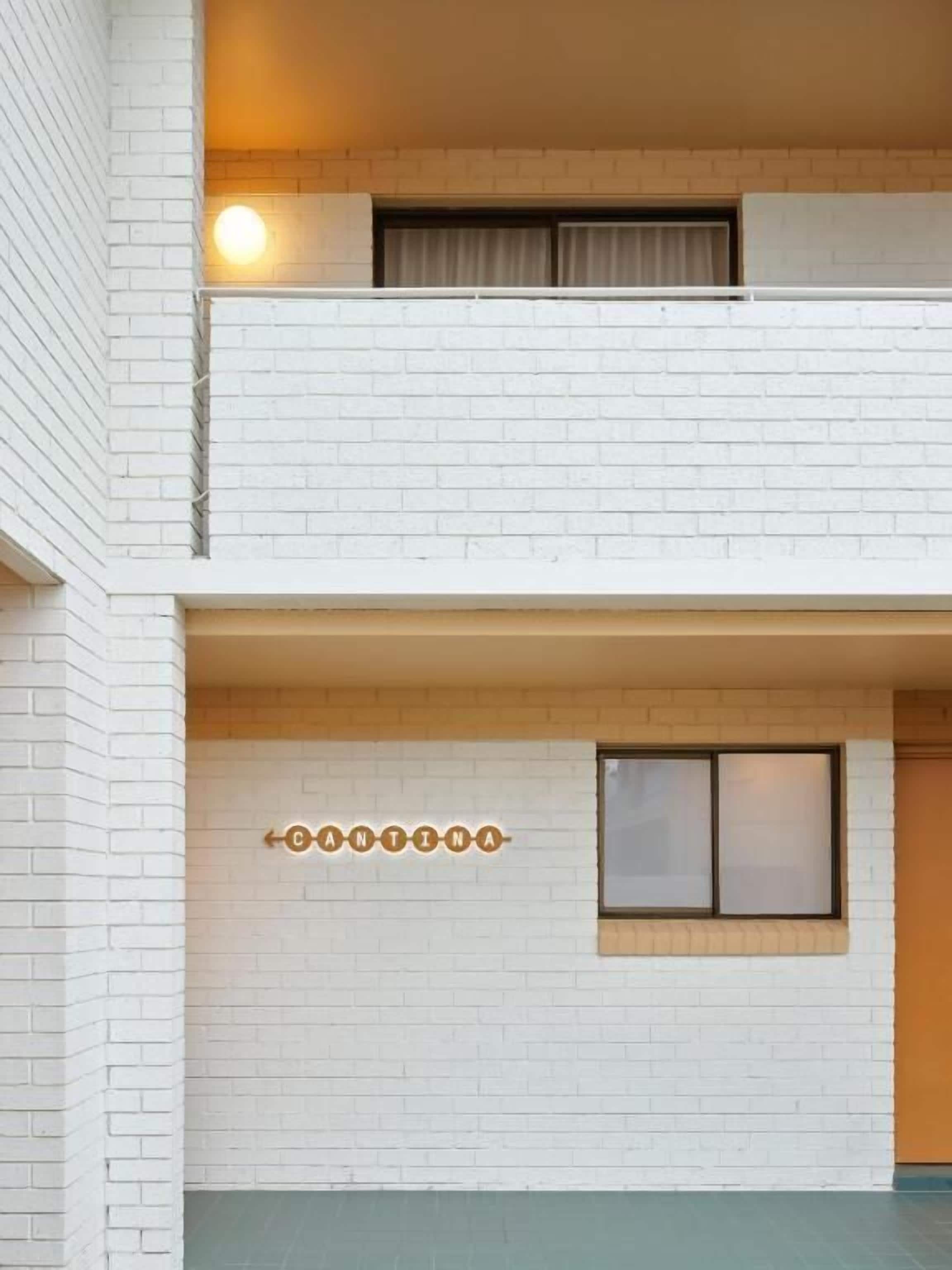 A multi-story building with white brick walls and a balcony on the upper floor.