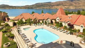 Un resort con piscina, sillas de descanso y vistas a un lago y montañas.