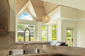 A kitchen with a large window, a sink, and a ceiling fan.