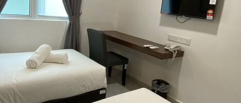 A hotel room with two beds, a desk, a chair, a TV, and an air conditioning unit.