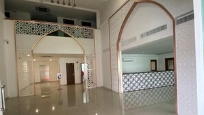 Um hall amplo com teto alto, piso ladrilhado e arcos decorativos.