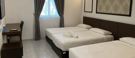 Ein Hotelzimmer mit zwei Betten, einem Schreibtisch und einem fensterbepflanzten Fenster.