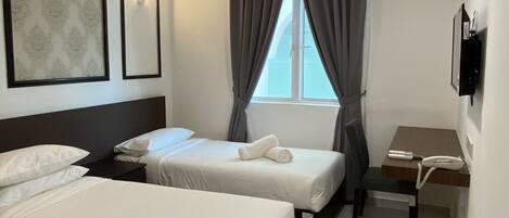 A hotel room with two beds, a desk, a chair, a phone, and a window with curtains.