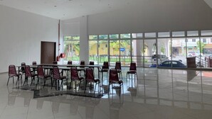 Um espaço interno amplo, com uma mesa comprida e cadeiras, janelas grandes e um design moderno e limpo.