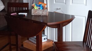 Ein Essbereich mit einem Holztisch und Stühlen, einer Snackkörbchen sowie einer weißen Tür im Hintergrund.