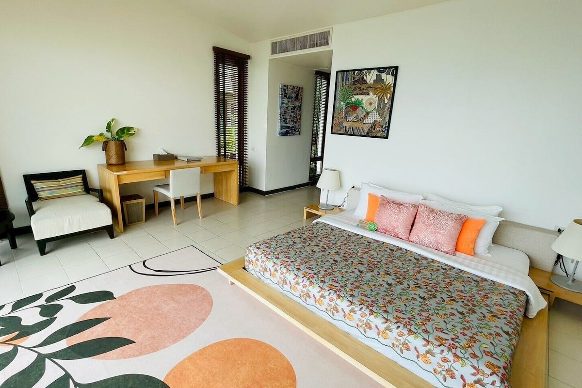 A bedroom with a bed, bedside tables, a desk, and a chair.