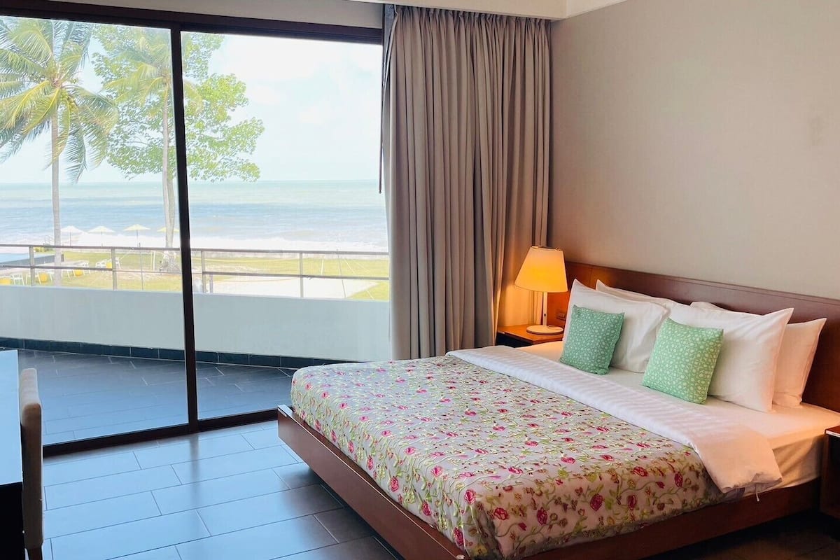A hotel room with a bed, a desk, and a view of the ocean.