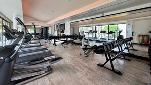 A spacious gym with treadmills, weight machines, and a large mirror reflecting the equipment. - TASALA cabana (Tha Sala)