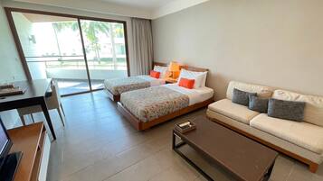 A hotel room with two beds, a sofa, a coffee table, and a desk.