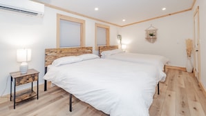 Ein Schlafzimmer mit zwei Betten, Holz-Kopfteilen, einem Nachttisch mit Lampe und einer hängenden Makramee-Dekoration.