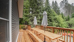 Eine Holzterrasse mit Picknicktischen und Sonnenschirmen, umgeben von dichtem Wald.