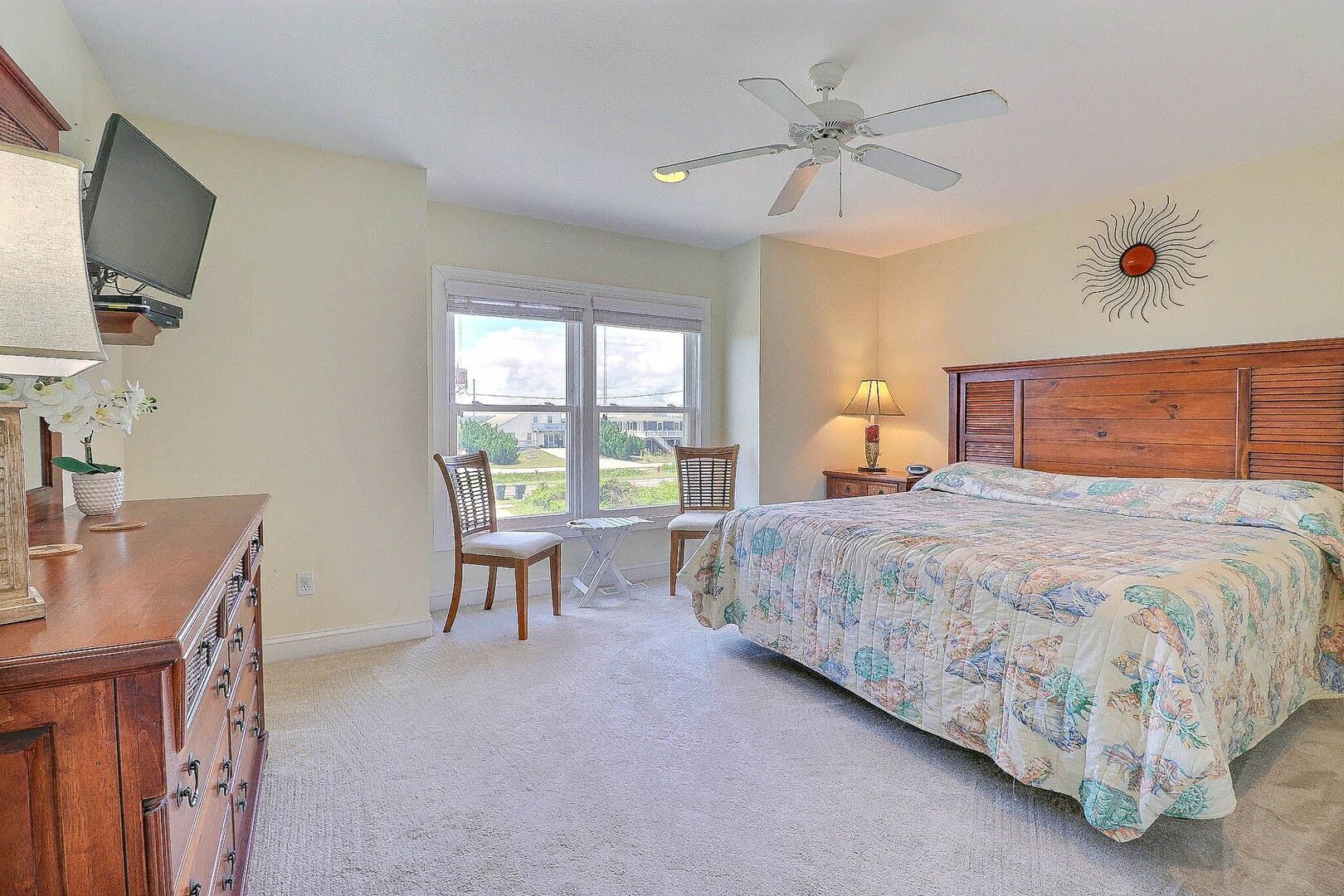 Une chambre à coucher comprenant un lit, un bureau, une chaise, un téléviseur et une fenêtre donnant sur l’extérieur.