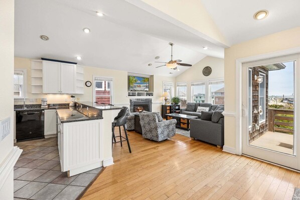 A spacious open-plan living area with a kitchen, dining space, and a balcony with a view.
