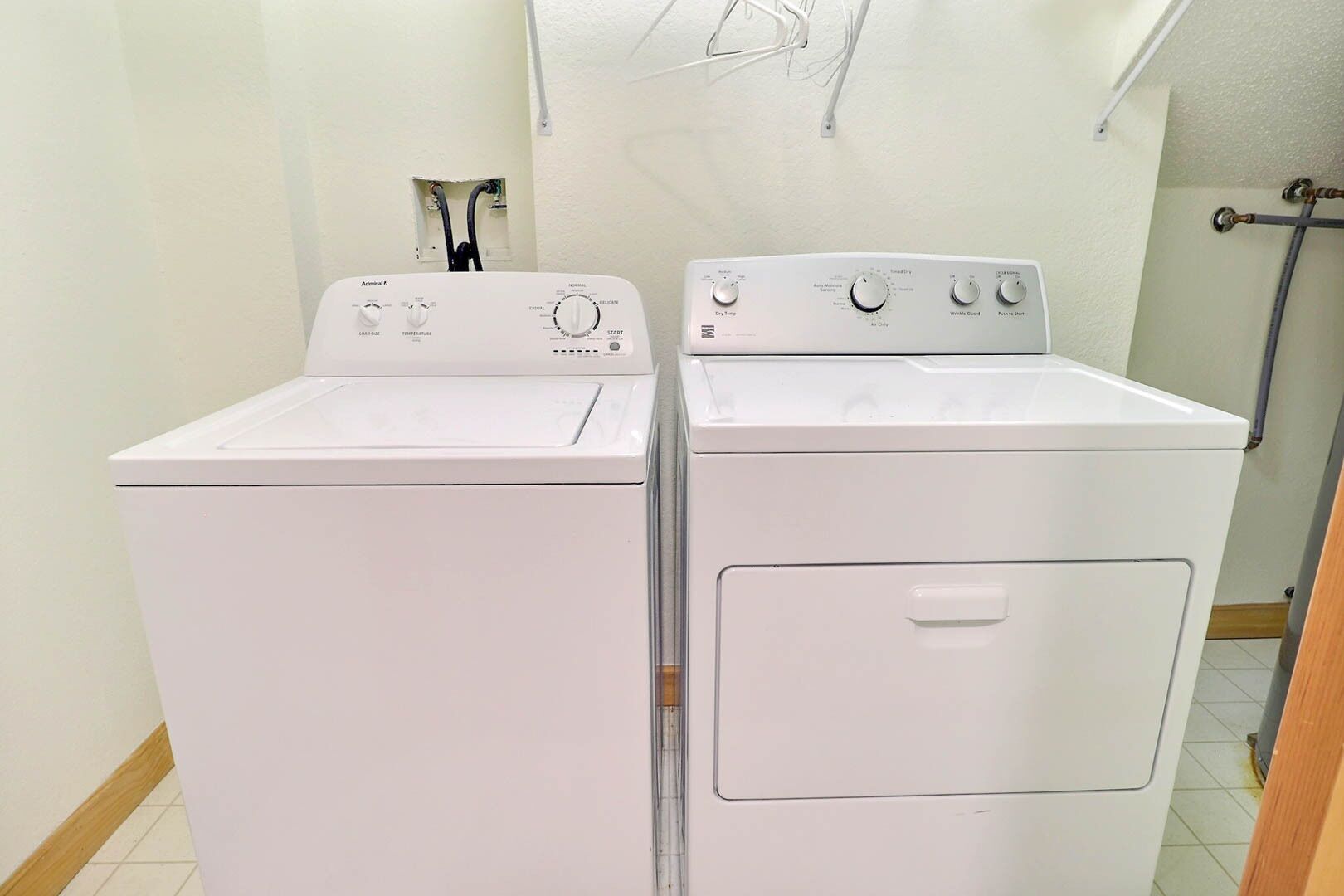 Une buanderie équipée de deux machines à laver à chargement frontal blanches et d’un sèche-linge.