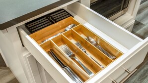 A kitchen drawer with utensils organized in compartments.