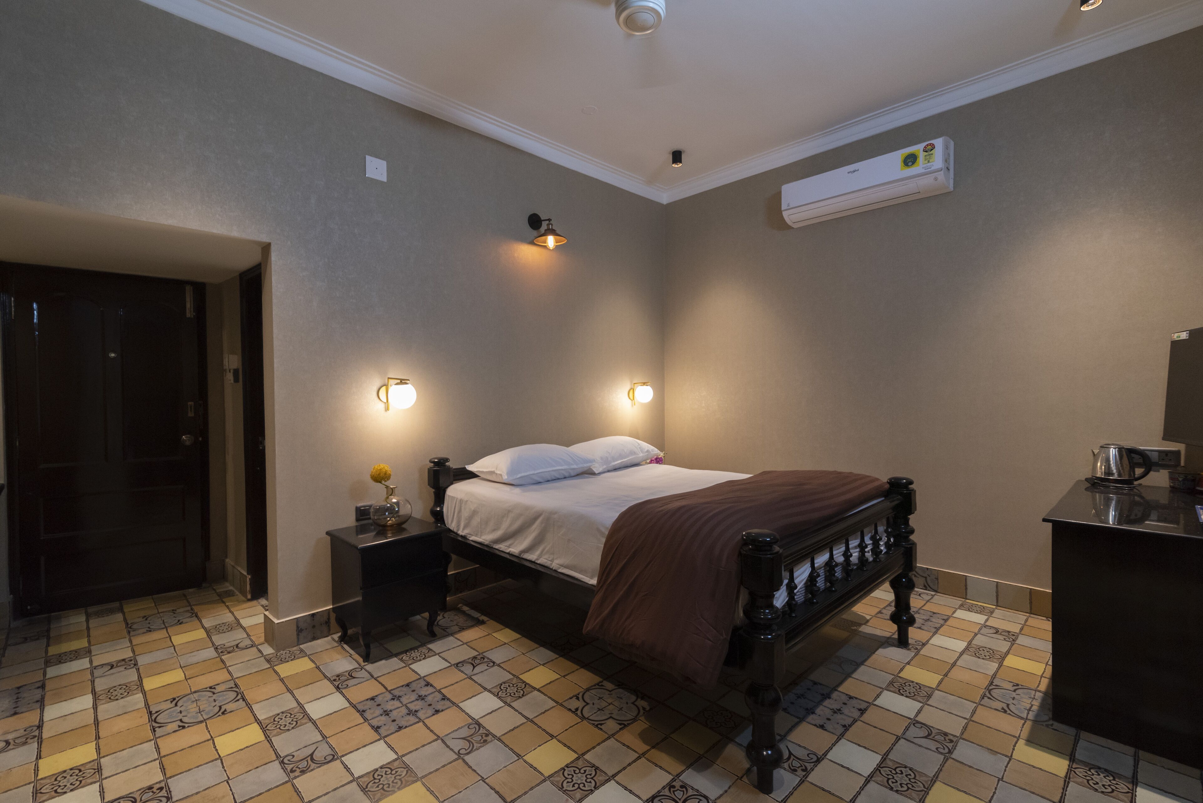 Une chambre à coucher comprenant un lit, des tables de chevet, un climatiseur et un sol carrelé.