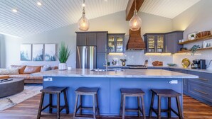 Een moderne keuken met een groot eiland, barkrukken en hanglampen.