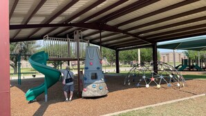 A playground with a slide, climbing wall, and swings.