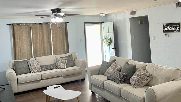 A living room with two beige sofas, a white coffee table, and a ceiling fan.