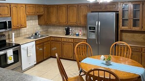 A kitchen with wooden cabinets, a stainless steel refrigerator, a dishwasher, a microwave, and a granite countertop.