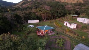 Una casa con techo verde, rodeada de abundante vegetación y colinas.