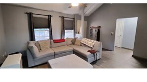 A living room with a sectional sofa, a small table, and a door leading to another room. - Mt Lassen and the great outdoors (Shingletown)
