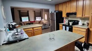 A kitchen with wooden cabinets, a central island, and a refrigerator. - Mt Lassen and the great outdoors (Shingletown)