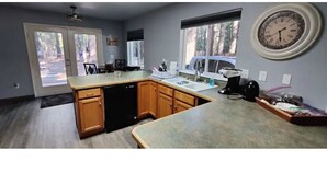 A kitchen with wooden cabinets, a dishwasher, a sink, and a clock on the wall. - Mt Lassen and the great outdoors (Shingletown)