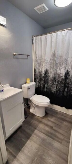 Un baño con inodoro, lavamanos y cortina de ducha con diseño de árbol.