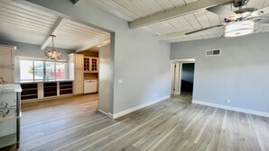 Una cocina amplia con piso de madera, armarios blancos y ventilador de techo.