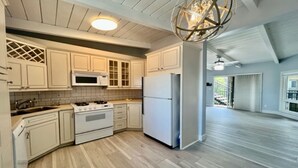 Una cocina con armarios blancos, un microondas, un refrigerador y una estufa.