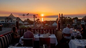 Un restaurante al aire libre con mesas listas para comer, con vista a una puesta de sol.