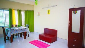 A dining area with a table set for four, a red sofa, and a red door. - 💗AC,ATTACH BATH ROOM,NEAR LALMATIA MOHAMADPUR (Dhaka)