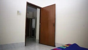 Una habitació amb una porta de fusta, un paviment de rajoles i una catifes amb franges de colors.