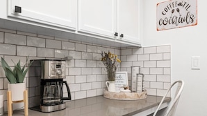 A kitchen with white cabinets, a coffee maker, a plant, and a sign that says "Coffee & Cocktails". - Unrivaled Location, Hot Tub, Huge Patio w/ Gazebo and Couches, Pool Table, Ping Pong, Walk to Dundee (Dundee)