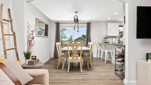 A modern kitchen with white cabinets, a built-in wine rack, and a dining area with a wooden table and chairs. - Unrivaled Location, Hot Tub, Huge Patio w/ Gazebo and Couches, Pool Table, Ping Pong, Walk to Dundee (Dundee)
