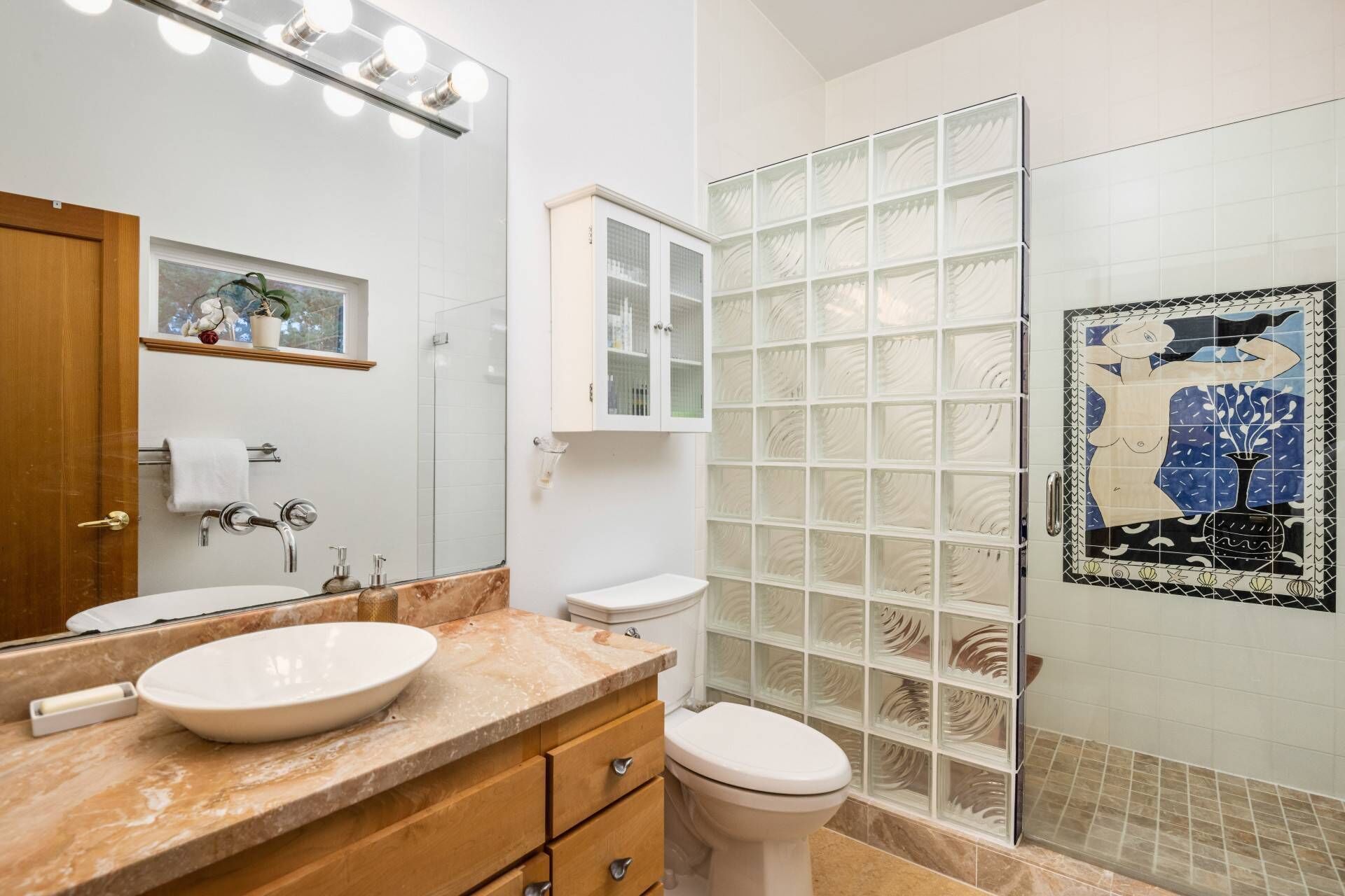 A bathroom with a vanity, sink, mirror, and toilet.