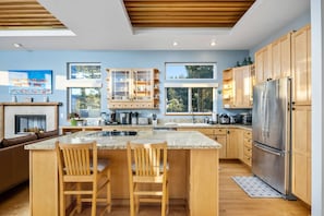 Cozinha moderna com armários de madeira, uma geladeira de aço inoxidável e uma ilha central com banquetas.