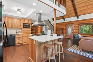 L’intérieur d’une cabane en rondins comprend une cuisine, un coin repas et un escalier.