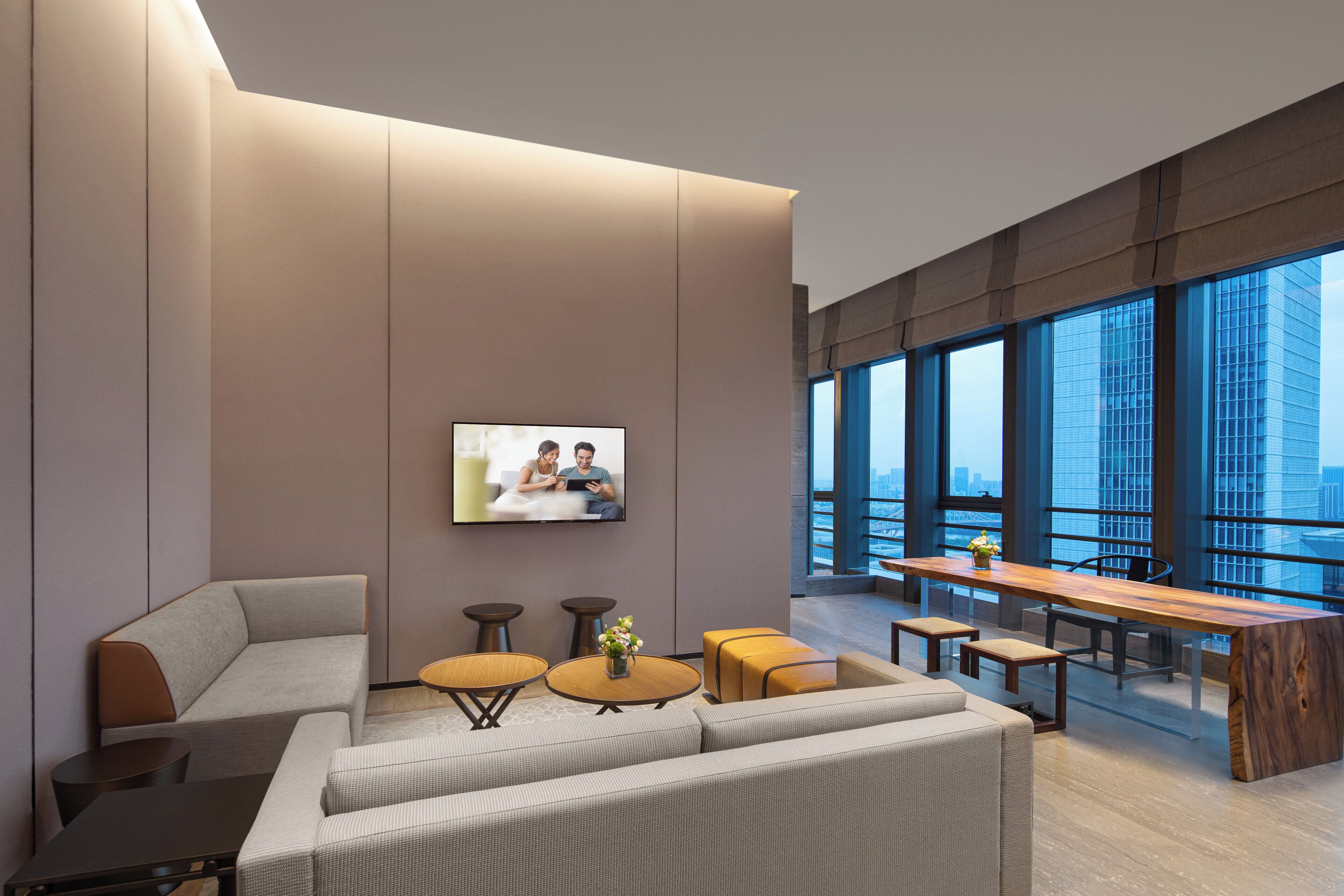A modern lounge area with a sofa, coffee table, and a long wooden table.