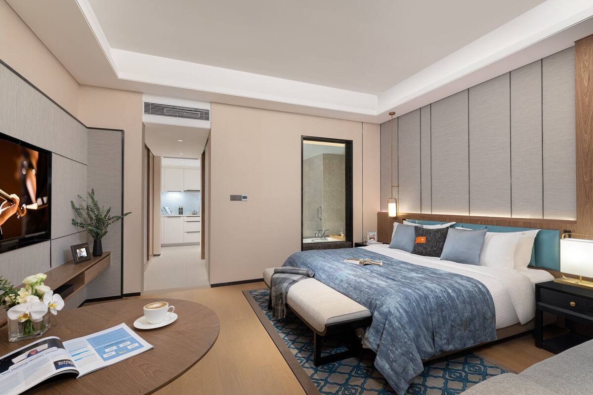 A modern hotel room with a large bed, bedside table, and a TV.