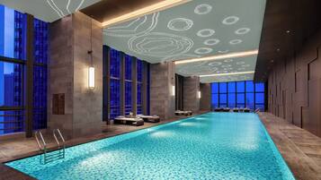 Een binnenzwembad, ligstoelen bij het zwembad