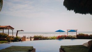 Vista de la piscina con una playa y el océano al fondo.